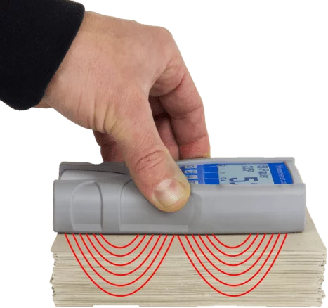 humimeter PMP dociśnięty dłonią do stosu papieru - zaznaczona strefa pomiaru